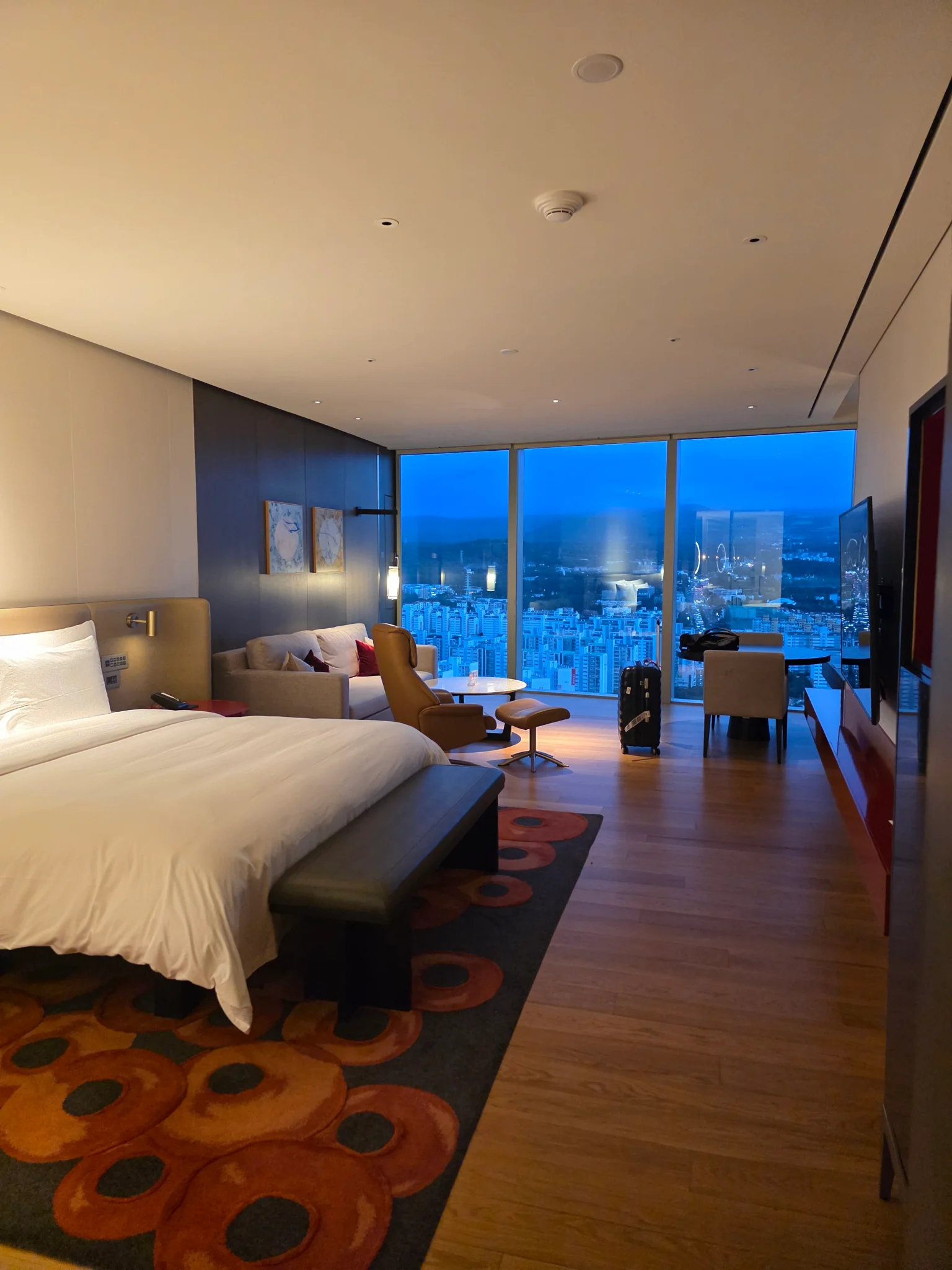 넓은 창으로 도심 야경이 보이는 호텔 객실 내부