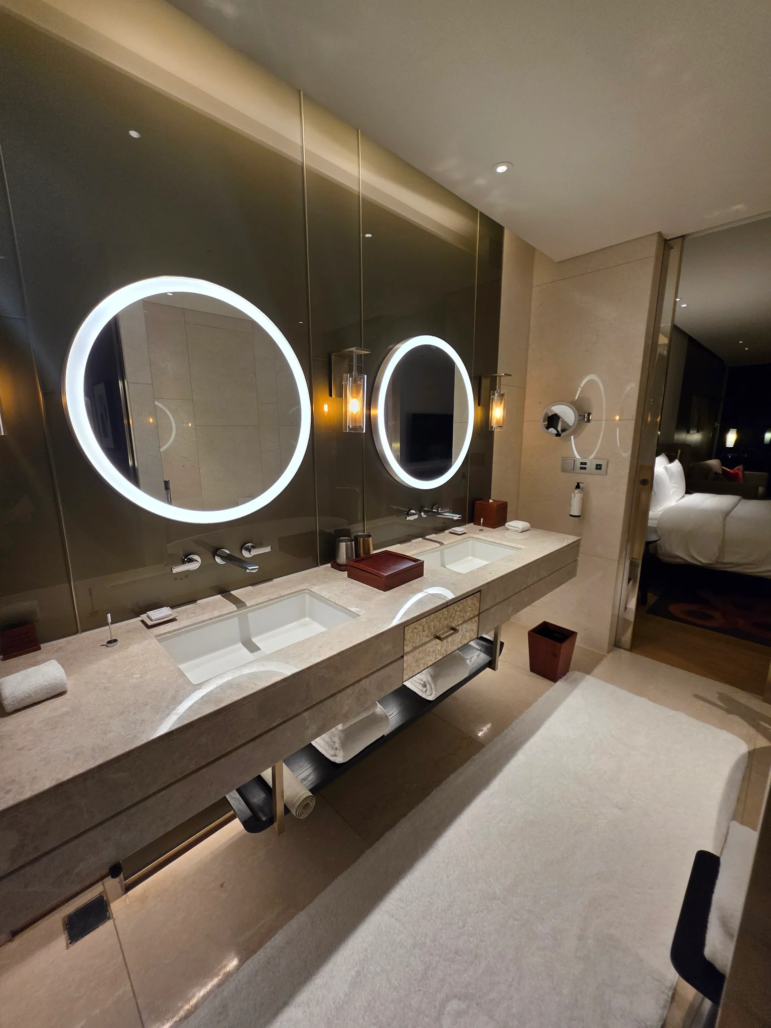 LED 조명이 내장된 원형 거울과 대리석 더블 세면대가 있는 고급 호텔 욕실