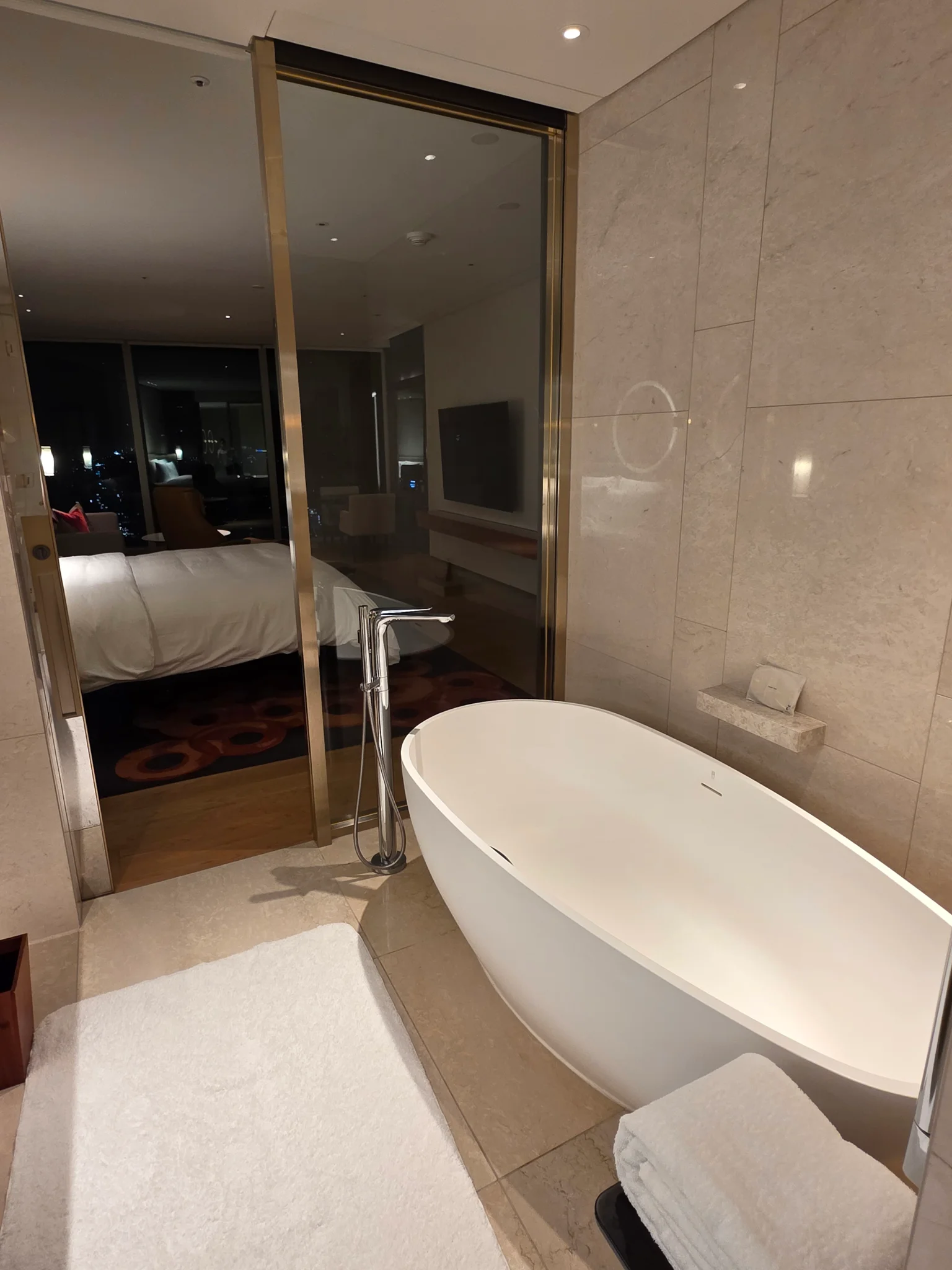 베이지 대리석으로 마감된 고급 호텔 욕실의 화이트 독립형 욕조