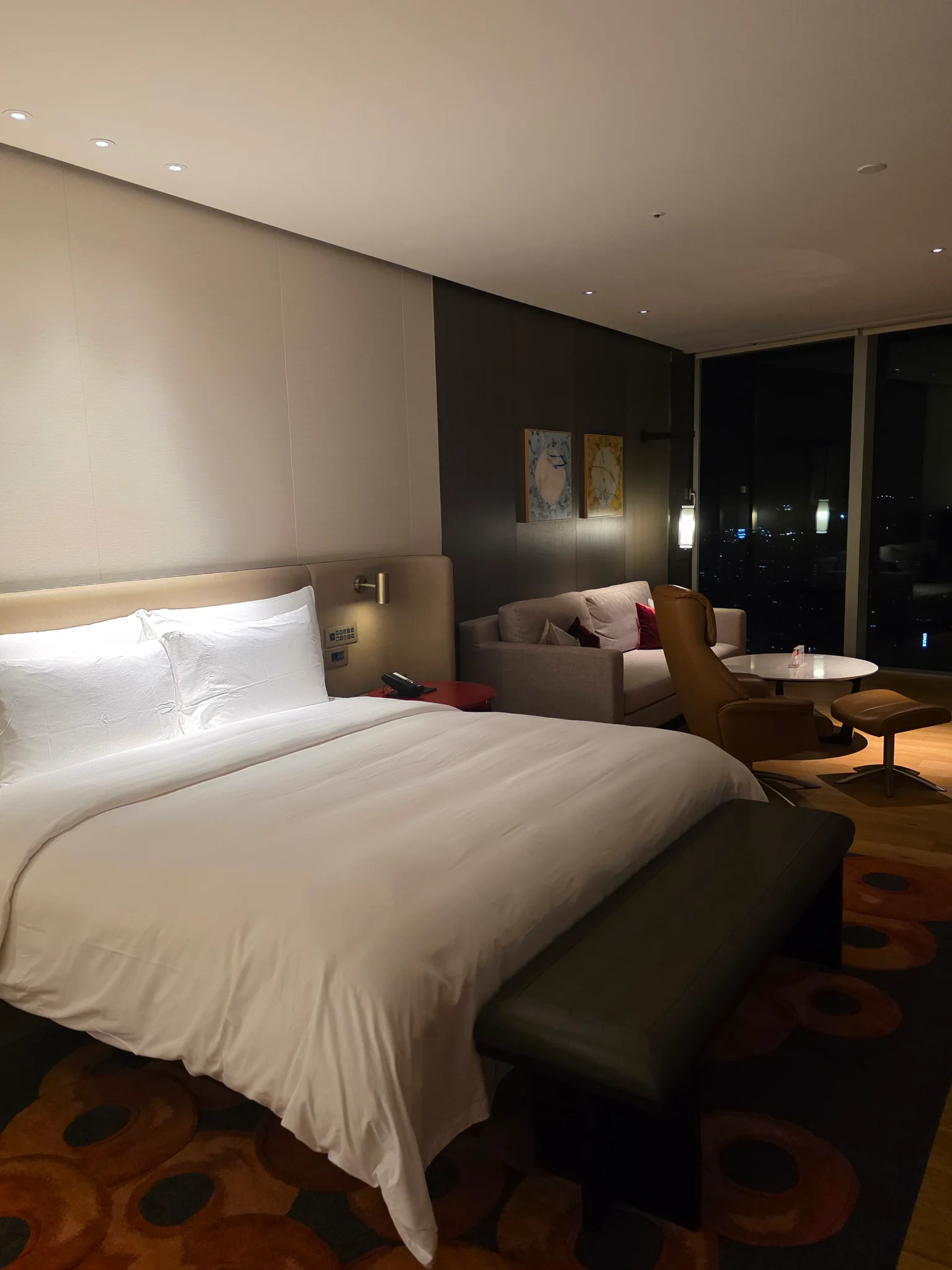 전면 유리창으로 도심 야경이 보이는 고층 호텔 객실 내부