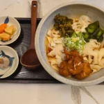 검은 쟁반에 카레우동과 반찬이 담긴 일본식 정식