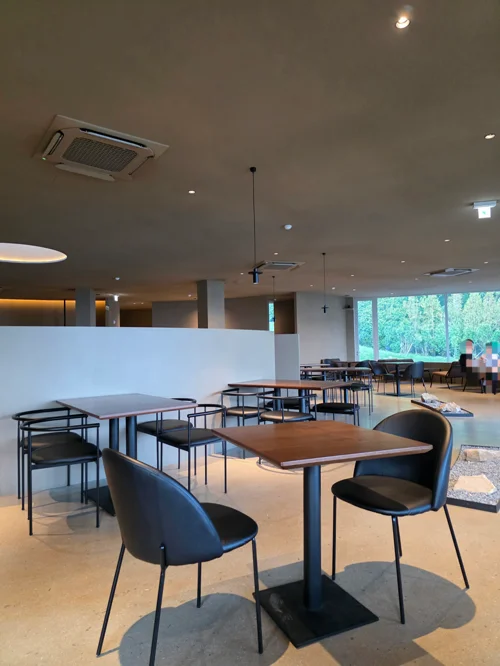 창가에 녹지가 보이는 현대적인 카페 내부 좌석 공간