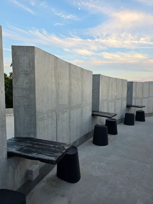 콘크리트 벽과 검은색 벤치가 배치된 야외 공간의 저녁 풍경