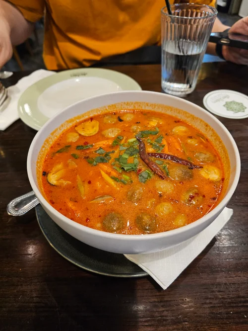 고수와 붉은 고추가 고명으로 올려진 주황색 커리 수프