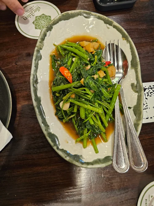 녹색 테두리 접시에 담긴 간장 소스 청경채 볶음, 마늘과 고추 곁들임