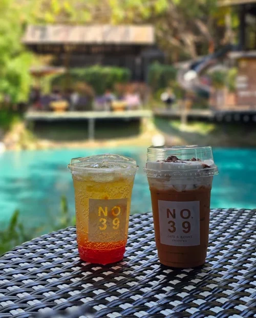터키색 수영장이 보이는 야외 테라스에 놓인 NO.39 브랜드 음료 두 잔