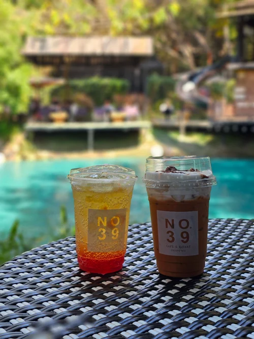 터키색 수영장이 보이는 야외 테라스에 놓인 NO.39 브랜드 음료 두 잔
