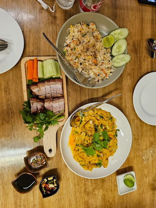 나무 테이블 위 태국 스타일 볶음밥, 카레 볶음밥, 구운 삼겹살 요리