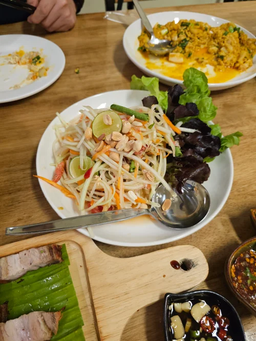 나무 테이블 위 파파야 샐러드와 카레 볶음밥 등 태국 음식