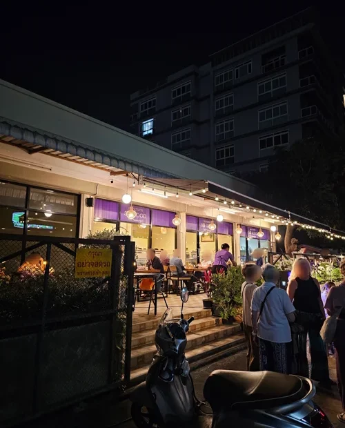 스트링 조명과 네온사인이 켜진 야외 레스토랑에서 손님들이 식사하는 밤 풍경