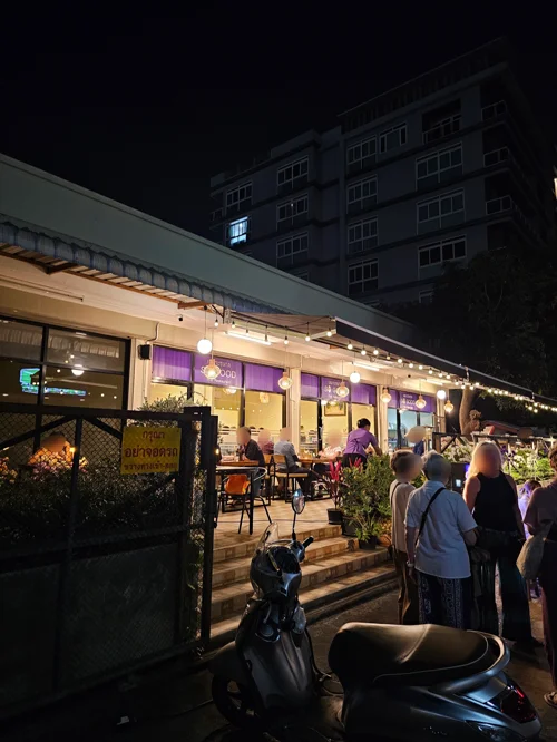 스트링 조명과 네온사인이 켜진 야외 레스토랑에서 손님들이 식사하는 밤 풍경