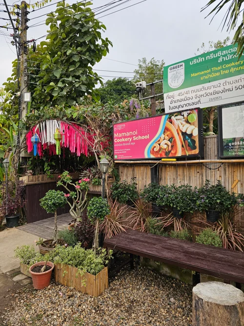 마마노이 쿠킹 스쿨 간판과 열대 식물로 꾸며진 정원 입구