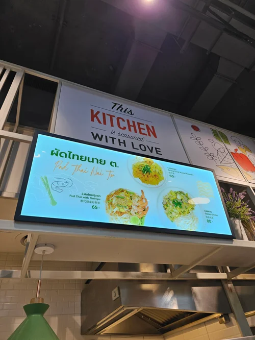 팟타이 메뉴가 표시된 청록색 디지털 메뉴판이 있는 태국 레스토랑 주문 카운터