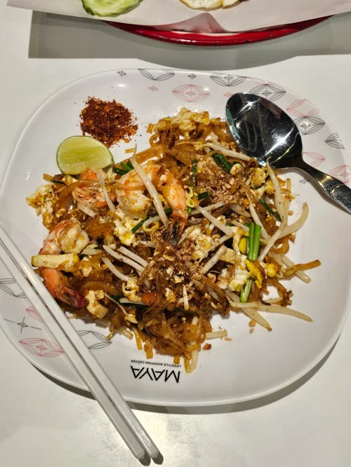 새우와 달걀, 숙주나물이 들어간 팟타이 요리가 담긴 흰 접시