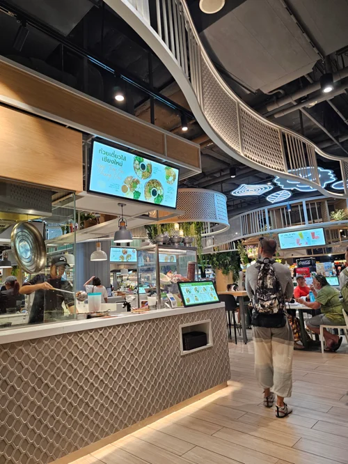 곡선형 천장과 우드톤 주문 카운터가 있는 현대식 푸드코트 내부