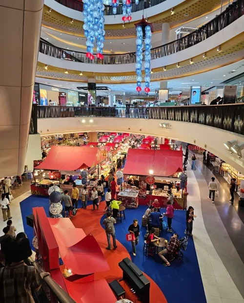 복층 쇼핑몰 중앙에 빨간색 파란색 카펫과 풍선 장식으로 꾸며진 크리스마스 이벤트 공간