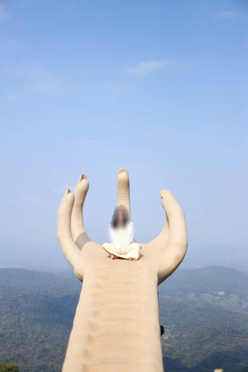 파란 하늘 배경으로 손을 들어올려 손가락 사이로 산맥 풍경을 담은 사진