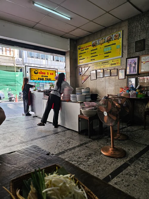 노란 간판이 있는 태국 로컬 국수집 내부, 카운터 앞에 손님들이 주문 중