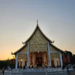 황혼 하늘을 배경으로 서 있는 화려한 모자이크 장식의 태국 불교 사원