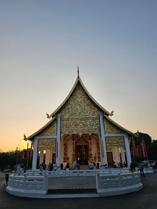 황혼 하늘을 배경으로 서 있는 화려한 모자이크 장식의 태국 불교 사원