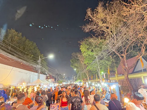 별이 보이는 밤하늘 아래 가로등과 노점 조명이 빛나는 야시장에서 사람들이 식사를 즐기는 모습