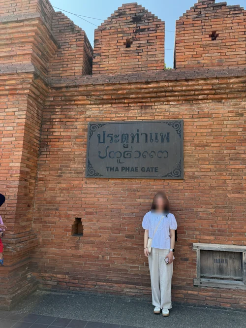 치앙마이 타패 게이트의 붉은 벽돌 성벽 앞에서 포즈를 취한 여행자