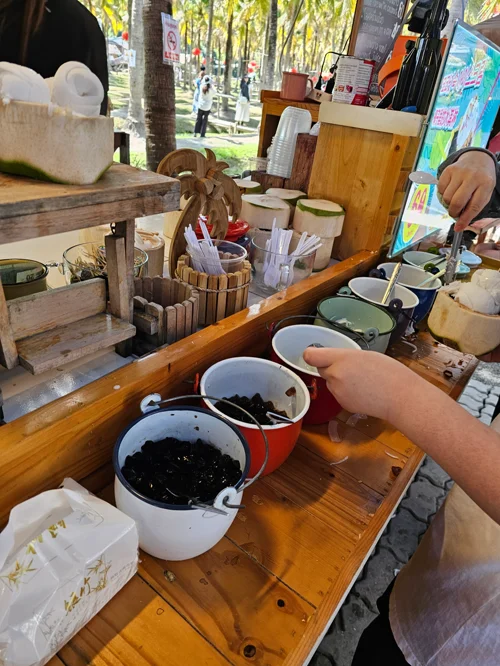 공원에서 진행되는 도자기 물레 체험 부스, 나무 작업대 위 점토 용기들