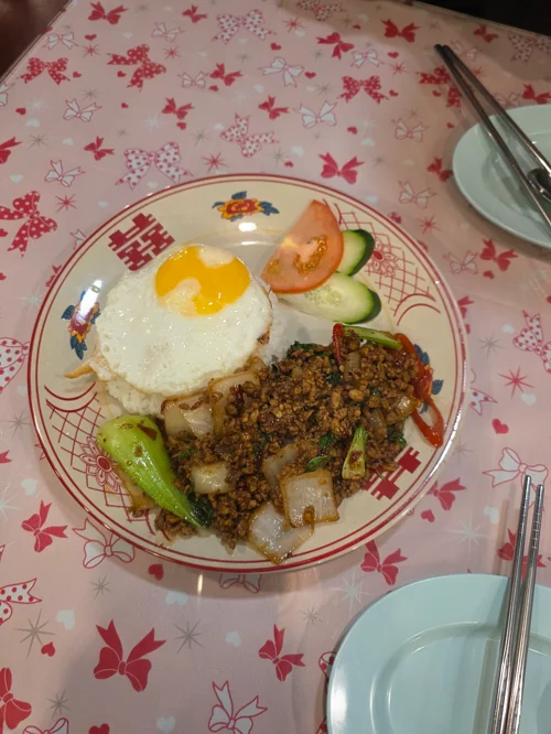 반숙 계란이 올려진 태국식 바질 볶음밥과 오이, 토마토가 담긴 접시