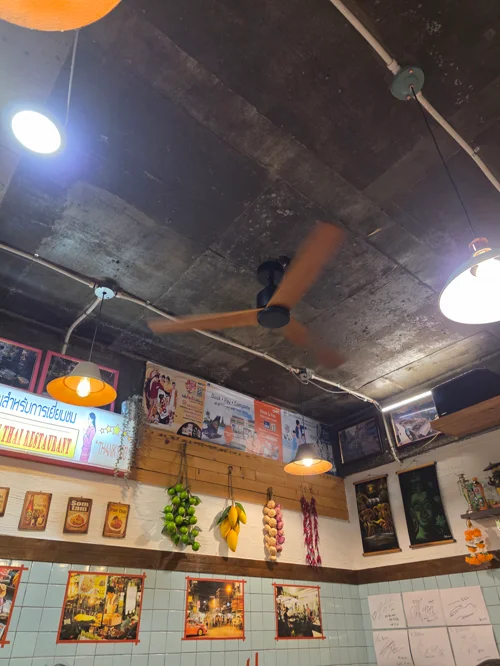 콘크리트 천장과 오렌지 선풍기, 빈티지 포스터로 꾸민 레트로 음식점 내부