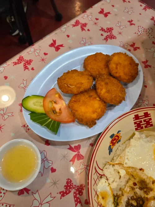 흰 접시에 담긴 황금빛 치킨 너겟 5개와 토마토, 오이 장식