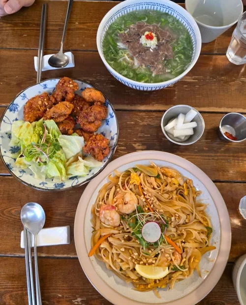 테이블 위 팟타이, 닭강정, 쌀국수가 담긴 베트남 식사 세팅