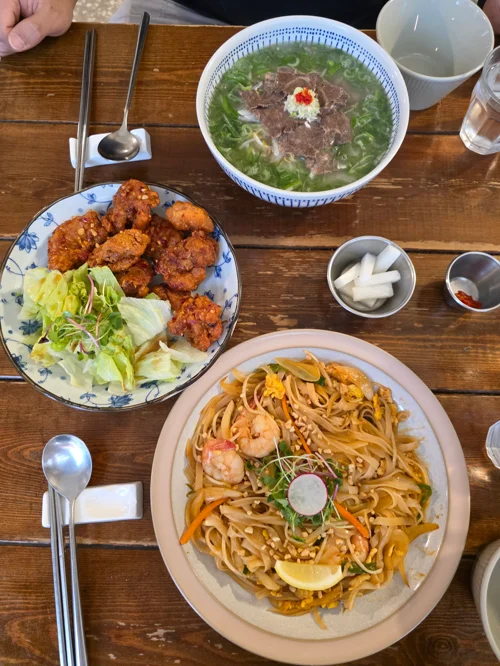 테이블 위 팟타이, 닭강정, 쌀국수가 담긴 베트남 식사 세팅