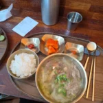 스테인리스 쟁반에 국물요리와 밥, 반찬이 담긴 한식 정식