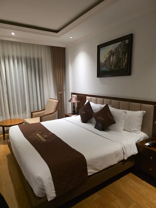 화이트 베딩과 브라운 베드러너가 있는 깔끔한 호텔 더블 침실