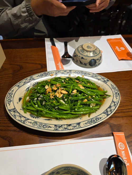 접시에 담긴 공심채 마늘 볶음, 청량한 초록색 채소와 마늘 토핑