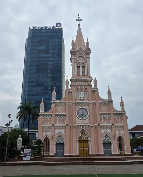 분홍색 고딕 양식의 다낭 대성당과 뒤편의 VietinBank 고층 빌딩