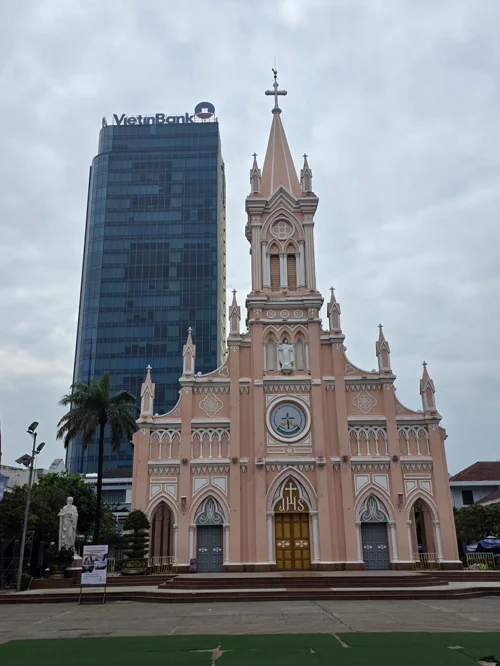 분홍색 고딕 양식의 다낭 대성당과 뒤편의 VietinBank 고층 빌딩