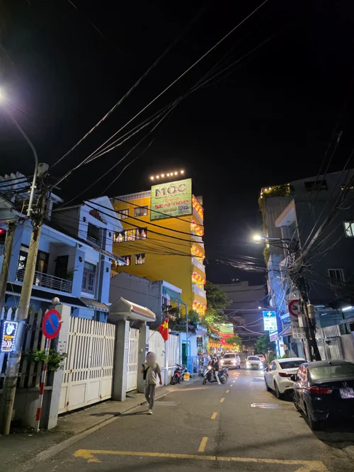 노란 조명의 MOC 게스트하우스 간판이 있는 베트남 골목길 야경