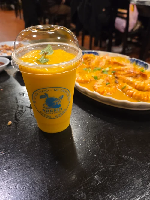 로켓 브랜드의 노란 망고 음료와 치즈 피자가 놓인 식탁