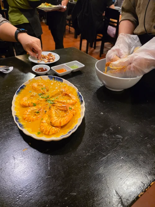 오렌지색 양념의 새우 요리와 일회용 장갑을 끼고 음식을 섞는 손