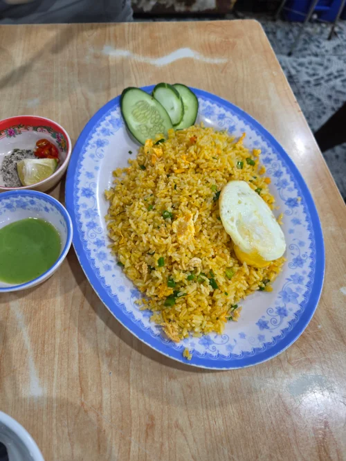 파란 접시에 담긴 노란색 볶음밥과 반숙 달걀, 오이 슬라이스