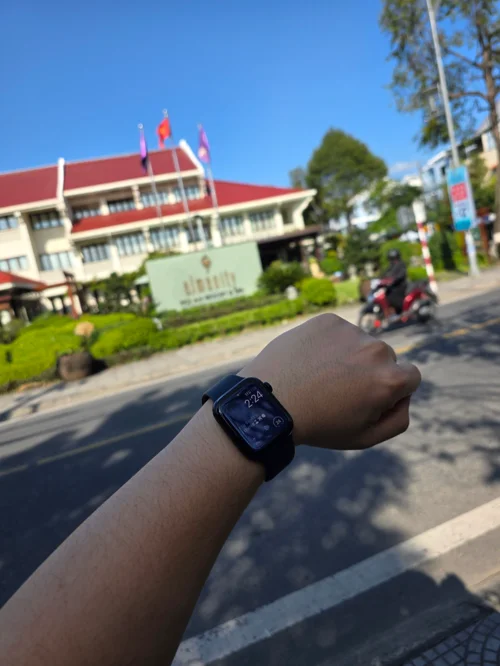 애플워치로 시간 확인하는 모습, 배경에 빨간 지붕 관공서 건물