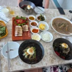 대리석 테이블에 비빔밥, 육회, 된장찌개 등 다양한 한식 메뉴가 차려진 모습