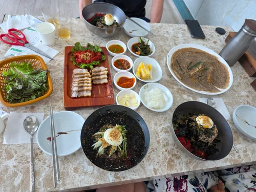 대리석 테이블에 비빔밥, 육회, 된장찌개 등 다양한 한식 메뉴가 차려진 모습