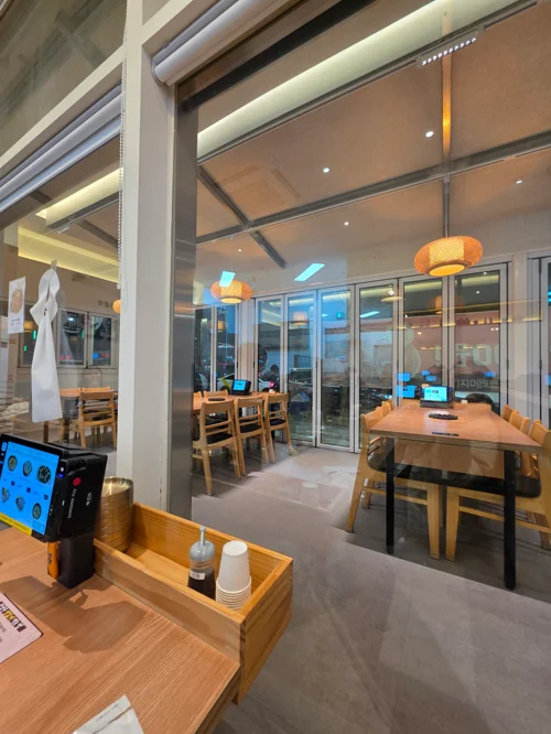 높은 천장과 원목 테이블, 컬러 조명이 있는 모던 카페 내부