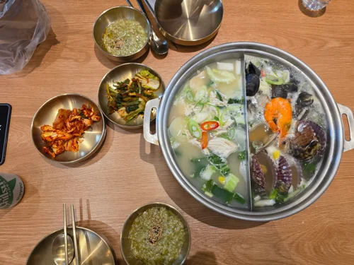 테이블 위 원형 냄비에 채소와 해산물이 담긴 샤부샤부 전골 세트