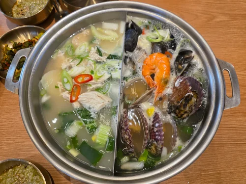 칸막이로 나뉜 냄비에 채소와 해산물이 각각 담긴 투톤 샤브샤브