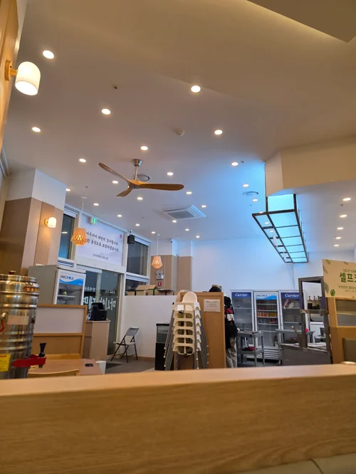 높은 천장과 다수의 조명이 있는 밝은 카페 실내 전경