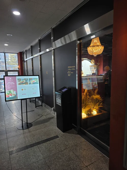 검은 유리문과 골드 샹들리에가 보이는 레스토랑 입구