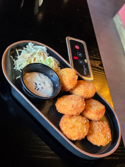 검은 타원형 접시에 바삭하게 튀긴 치킨 너겟과 마요네즈 소스가 담긴 모습